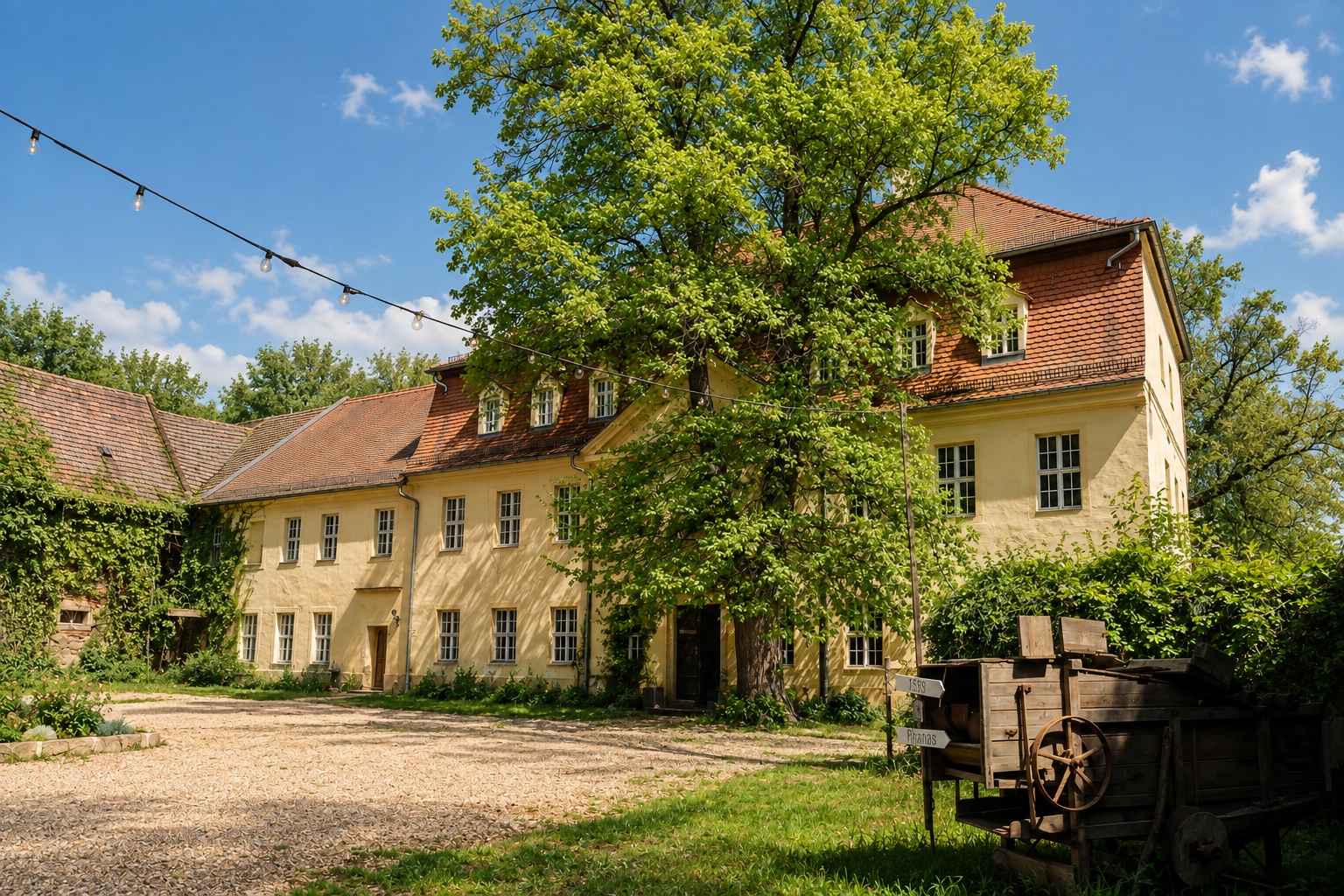 Das Gutshaus mit Lichterkette über dem Hof, davor der alte Leiterwagen